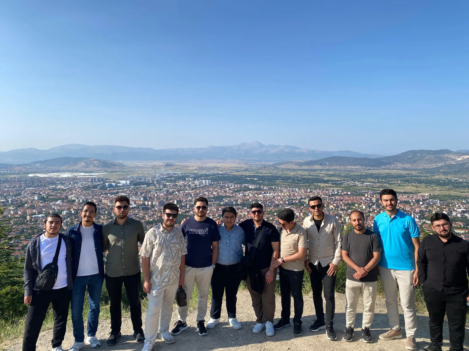 Müstesna Gençlik Kulübü üyeleri şehir ve dağ manzarası önünde birlikte